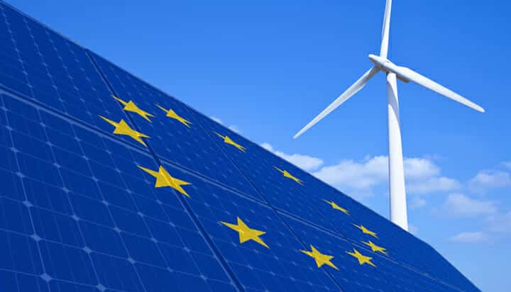 Picture of the European Union flag on solar panels and a wind turbine