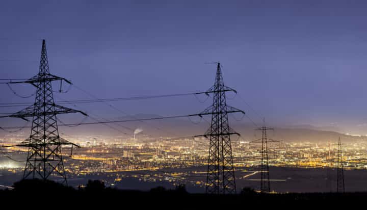 Power lines with a city lit up at night in the background